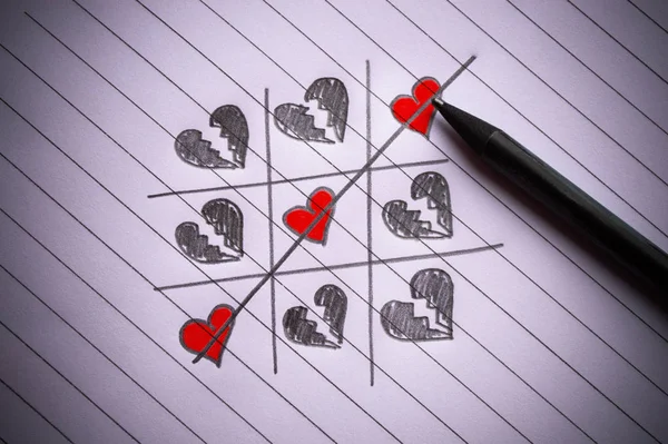 Tic-tac-toe game with a crossed line and hearts drawn on paper — 스톡 사진