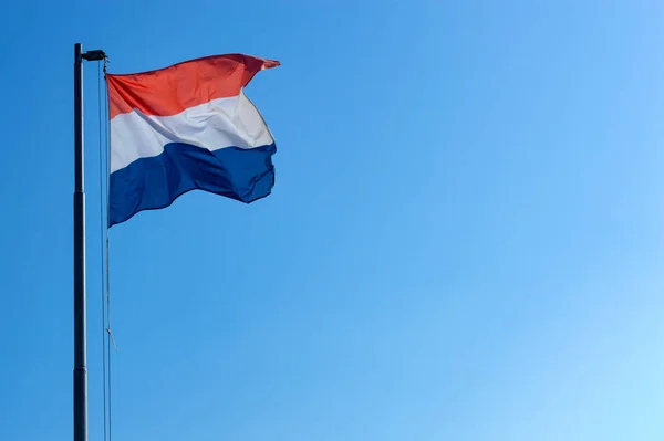 Голландський прапор летить вітром на блакитне небо. — стокове фото