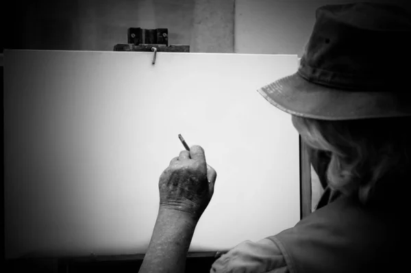 Viejo artista pinta un cuadro en un caballete —  Fotos de Stock