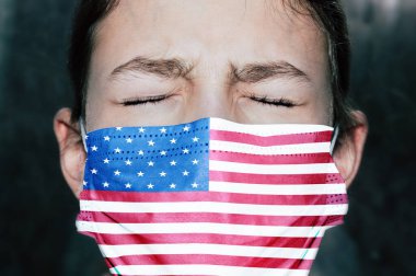 Amerikan bayrağıyla tıbbi maskeli üzgün genç kız.