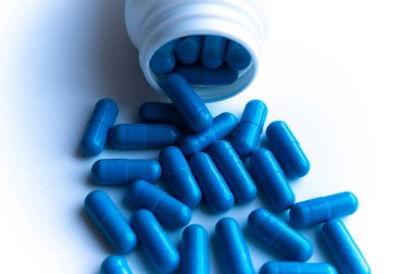 Beyaz arka planda dağınık haplarla dolu kavanoz.