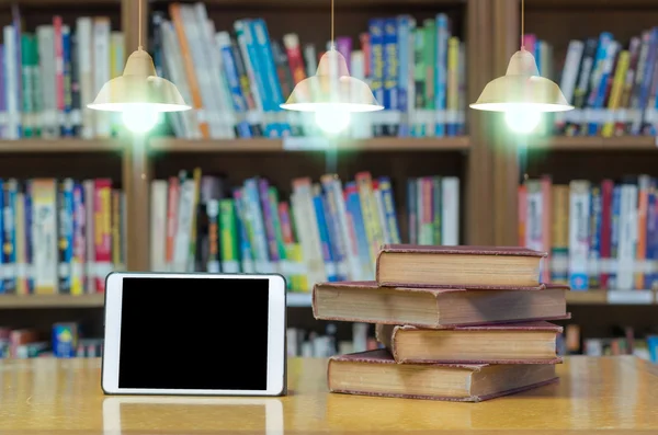 Libros antiguos en el escritorio en la biblioteca con tableta —  Fotos de Stock