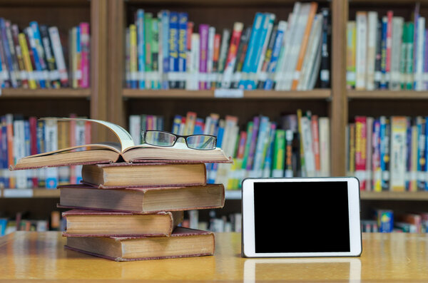 старые книги в библиотеке с планшетом
