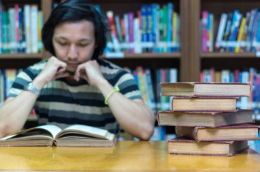 Adam kütüphanede kitap okuyor. 