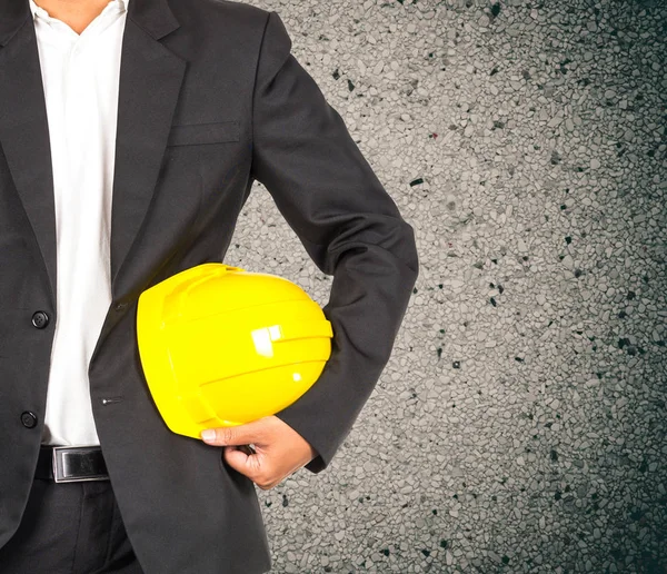 Инженер в костюме держит желтый шлем — стоковое фото