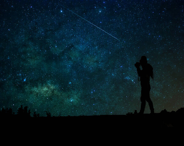Silhouette of a photographer who taking photo the milky way background