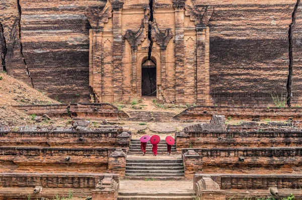 Três budistas segurando os guarda-chuvas vermelhos — Fotografia de Stock