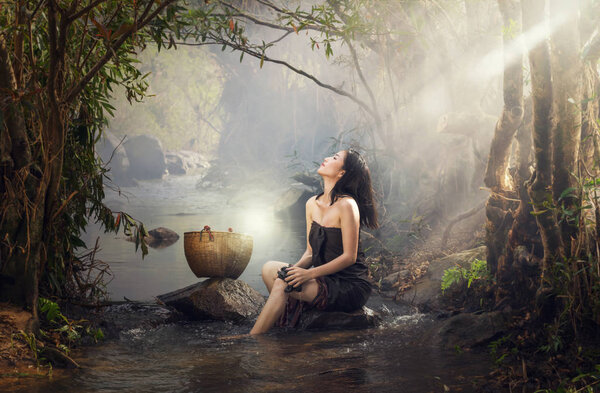 Beautiful Village woman sitting and washing clothes at stream of waterfall or river, countryside and Folkways concept