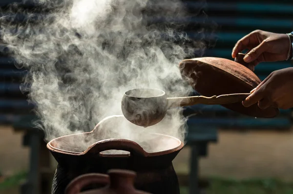 Hand holding dipper over pot — Stock Photo, Image