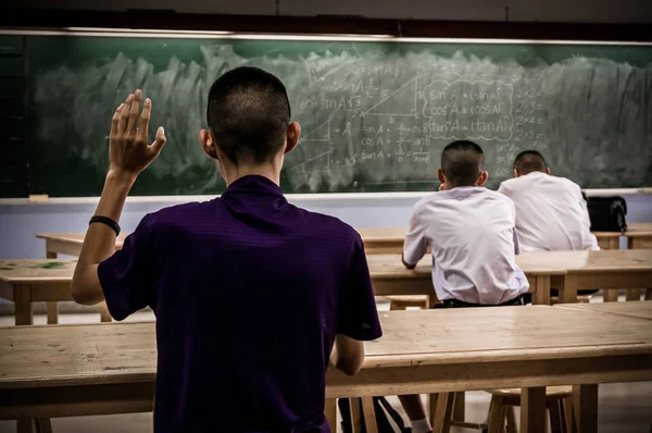 Студент с поднятой рукой в классе — стоковое фото