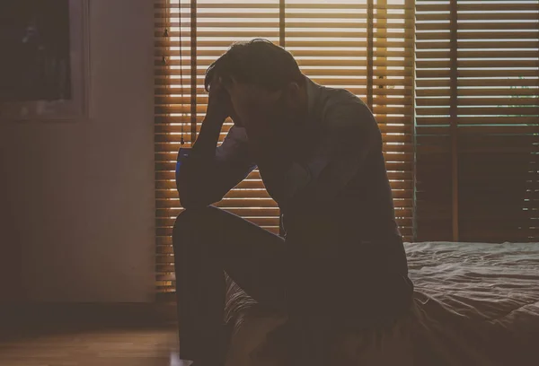 Депрессивный мужчина сидит на кровати — стоковое фото