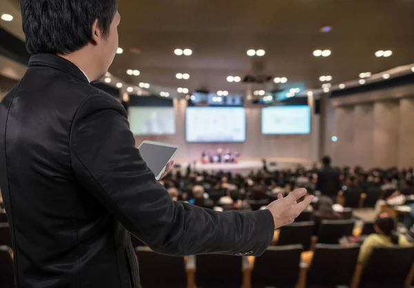 Geschäftsmann mit Tablet über verschwommenem Konferenzsaal — Stockfoto