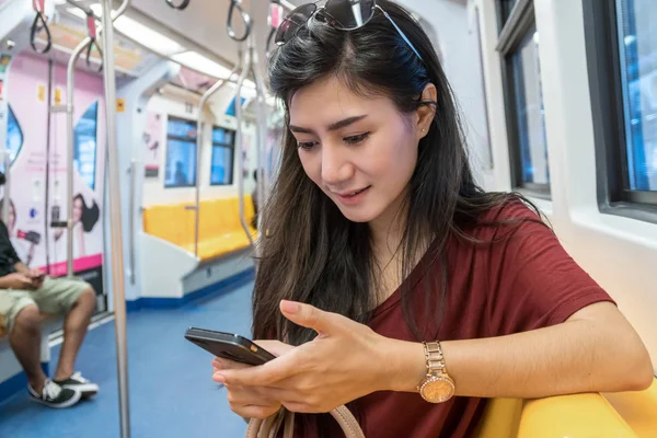 Asyalı kadın yolcu Smartphone kullanarak 