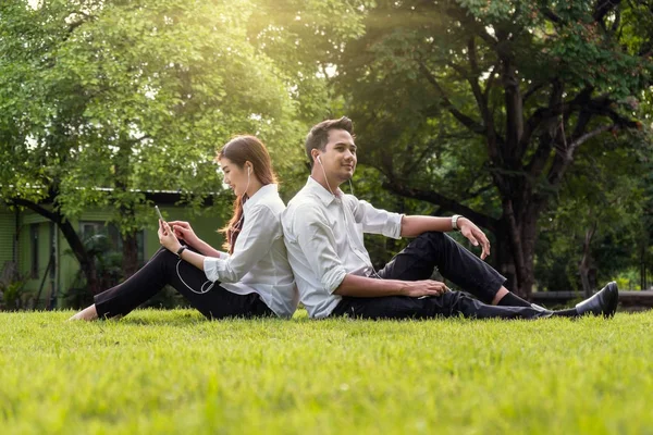 Casal ouvindo música no smartphone no parque — Fotografia de Stock