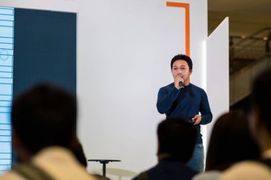 Sahne Alanı'ndaki iş veya eğitim seminer sunum ekran üzerinde rahat takım elbise ile Asya hoparlör