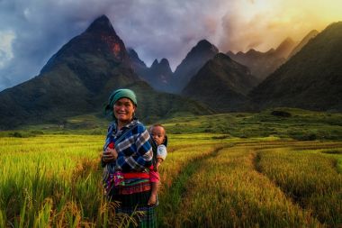 YENBAI - SEP 22 : Undefined Vietnamese Hmong with her baby standing in the rice fied on september 22, 2017 at cha vu near sapa,Yenbai province, northwest of Vietnam.  clipart