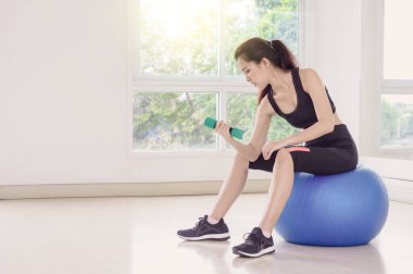 Genç Asyalı kadın bir topa egzersiz fitness salonunda spor kız kavramı yansıtmak