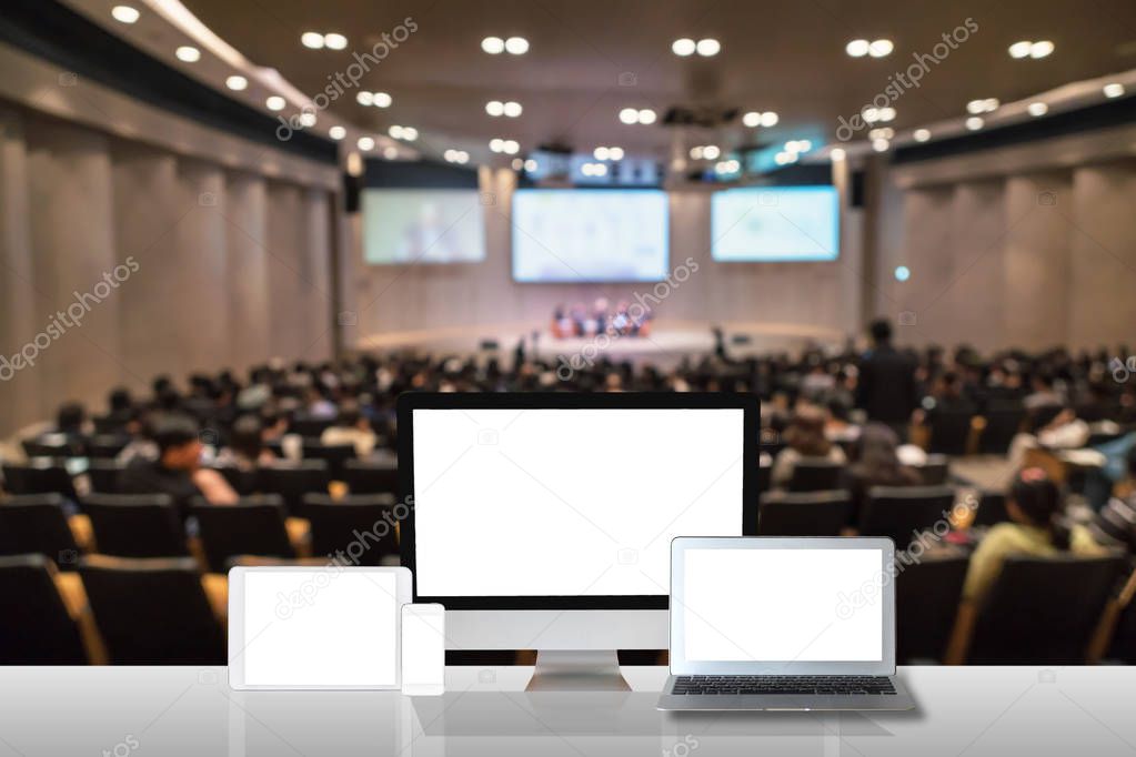 Computer set show on the white table over the Abstract blurred photo of conference hall or seminar room with attendee background, business technology and education concept