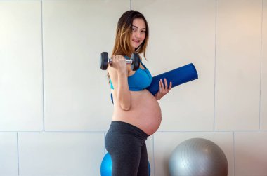 Asya hamile kadın portresi tutan büyük top, sağlıklı annelik kavramı spor salonunda egzersiz