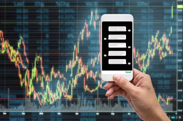 Female hand holding mobile phone showing the chat message before place the order over the Stock market chart,Closeup Stock market exchange data on LED display, business trading and technology concept