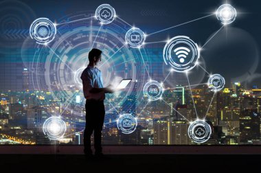 Ayakta ve akıllı şehir şeyler teknoloji Internet cityscape arka plan, teknoloji ve İnovasyon kavramı üzerinden iletişim kablosuz bağlanma gösterilen dizüstü bilgisayar kullanarak Asya iş adamı