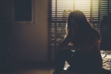 Oturma ve yatak ile düşük ışık çevre, dramatik kavramı koyu yatak odasında gerilmesini depresif kadın