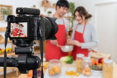 Mutlu Asya sevgilisi ya da çift kamera için fotoğrafçı ya da Video ve Live Streaming kavram mutfak oda pişirme video blog kayıt mikrofon ile profesyonel dijital Mirrorless fotoğraf makinesi