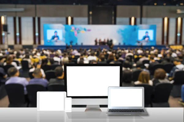 Computer set show on the white table over the Abstract blurred photo of conference hall or seminar room with attendee background, business technology and education concept