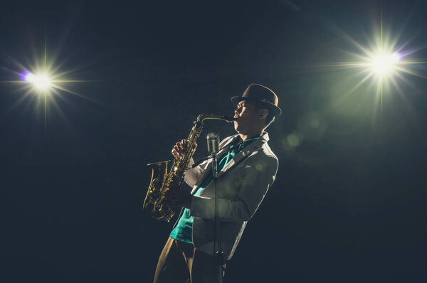 Asian Musician playing the Trumpet with spot light and lens flare on the stage, musical concept