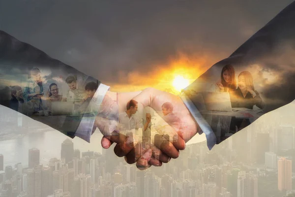 Double exposure of shaking hands of partner which have various group of Multiethnic Business people working and brainstorming over the Hong Kong Cityscape at the sunrise time, Business people concept