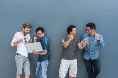 Asya grup ve çok ırklı iş casual elbise her teknoloji donanımı ile mutlu kullanarak insanlarla ve eylem açık duvar arka plan üzerinde insanlar iş grup kavramı kutlama