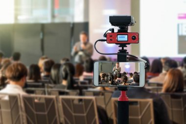 Closeup akıllı cep telefonu Live sahnede seyirci arkadan görünüş konferans salonu veya seminer toplantı, teknoloji canlı streaming ve yayın kavramı ile hoparlörler alarak