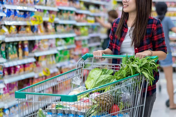 Closeup of Young Asian woman Hands holding trolley for shopping over store blurred in department store bokeh background