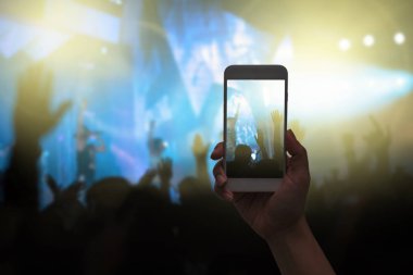 Kadın el telefon tutarak akıllı telefon video kayıt alarak veya konser akışı kalabalık siluetleri müzik fan-club ile gösteri el eylem, müzikal ve konser kavramı ile yaşamak