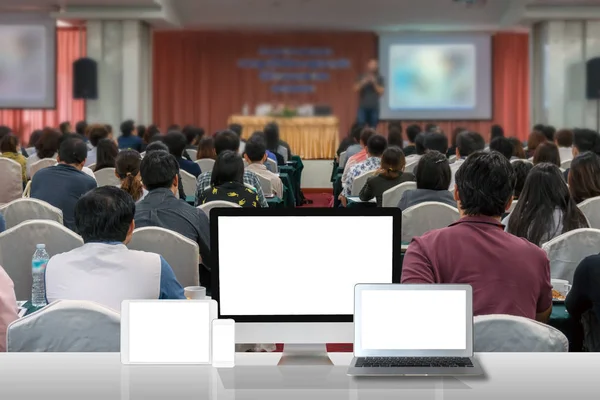 会議ホールやセミナー ステージのスピーカーの会議人の聴衆の後姿に白いテーブルの上のコンピューター セットを見るビジネス技術と教育のコンセプト — ストック写真