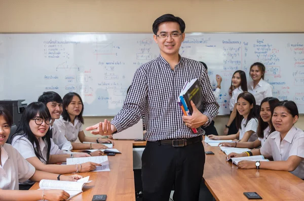 Portrait of Asian teacher standing when Giving Lesson to group of College Students in the classroom, University education concept