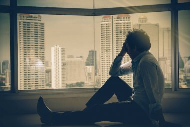 depresif adam baş cityscape arka plan üzerinde dramatik kavramı yanında belgili tanımlık pencere eşiği düşük ışık çevre ile iç gökdelen ellerde oturuyor