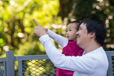 Asyalı kızı taşıyan ve öğrenme derin ormana işaret eden baba aile ve evde eğitim kavramı