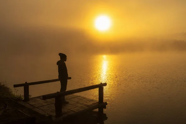 孤独の概念と劇的な日の出時に屋形船川湖に立っているシルエット落ち込んでいる人 — ストック写真