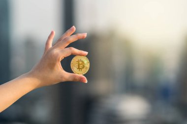 Arka plan, iş ve cryptocurrency kavramı Closeup el bitcoin cityscape üzerinde tutarak bulanık