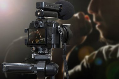 Mikrofon u tutan ve şarkı söyleyen Closeup Songer elinin mikrofon kayıt video blogu ile profesyonel dijital Aynasız fotoğraf makinesi, fotoğrafçı veya Video ve Canlı Akış konsepti için Kamera