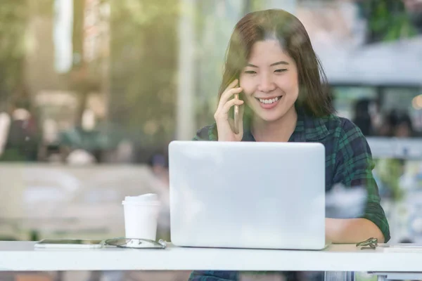 カジュアル スーツ話と近代的なオフィス ビジネスの所有者 起業家のコンセプトでガラスの横にあるデスクで幸福を駆る技術ノート パソコンで作業のアジア女性実業家の肖像画 — ストック写真