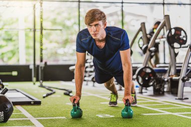Beden eğitimi spor kompleksinde spor yapan genç çeşitlilik, kol ve kardiyo çalışması, duruş pozisyonu ağırlık kaldırma, kettlebell üzerinde tahta atma. Spor ve sağlık konsepti