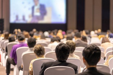 Konferans salonu veya Seminer Toplantı, iş ve eğitim yatırım kavramı hakkında sahnede hoparlörler dinleme seyirci arkadan görünüş