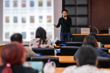 Asya Hoparlör veya konferans salonu veya seminer toplantı odasında projektör ekranı üzerinden sunum sahnede rahat takım elbise ile ders Seyirci, iş eğitimi ve Seminer kavramı