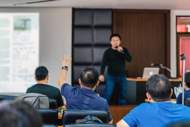 Konferans salonu veya Seminer Toplantı, iş ve eğitim kavramı sahne alanı'ndaki hoparlörden soruyu cevaplamak için el gösterilen seyirci arkadan görünüş