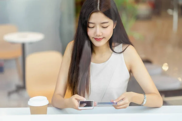 아시아의 커피숍에서 온라인 쇼핑을 휴대폰으로 카드를 사용하거나 윈도우 온라인 신용카드 — 스톡 사진