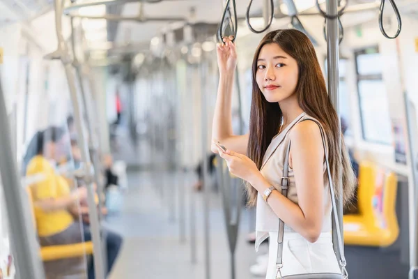 在大城市 日本人 中国人 韩国人的生活方式和日常生活 通勤者和交通观念中 年轻的亚洲女性乘客在乘坐地铁时 通过智能手机使用社交网络 — 图库照片