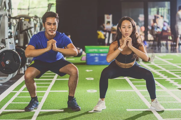 Couple young diversity working out in gym fitness sport complex, doing squad and cardio, posture position, Push up on weights, sports and healthcare,asian and asean people, concept