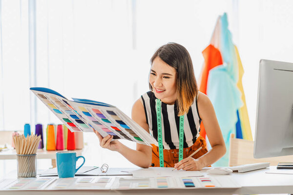 Young Asian designer woman choosing multicolor chart and writing noted at workplace, small business startup, Business owner entrepreneur, modern freelance job lifestyle concept. asean people